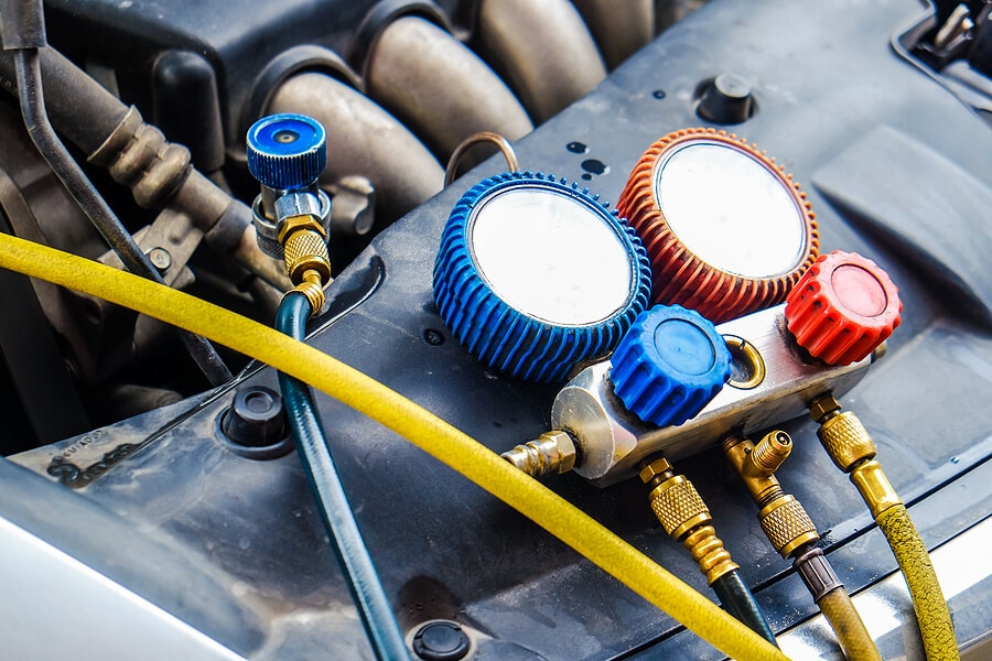 An air conditioner pressure gauge sits under the hood of a car. Come to Mevert Automotice for A/c & Heating repair.
