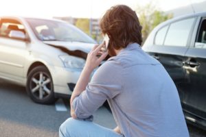 3 Signs Your Brake Master Cylinder Needs Replacement with Mevert Automotive & Tire Center in Steelville, Il. image of man on his phone kneeled down looking at his car that ran into the back of another car