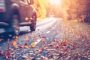 Your Guide to Illinois Fall Car Care in Steeleville with Mevert Automotive & Tire Center; image of red car driving on road during an autumn day