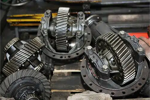 The engine and shaft with gears are disassembled. Black, metal engine parts