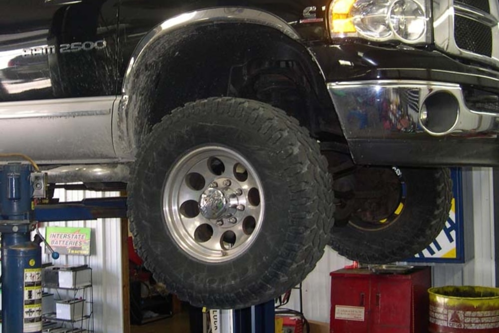 Fall & Winter Tire Services in Steeleville IL At Mevert Automotive. A close-up view of a vehicle tire in an auto repair shop, lifted on a hydraulic car lift.